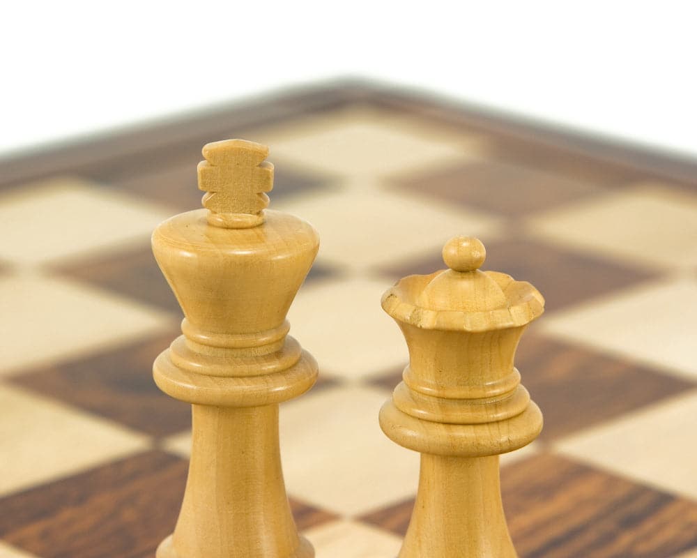 Close-up of King and Queen boxwood chess pieces on chessboard.