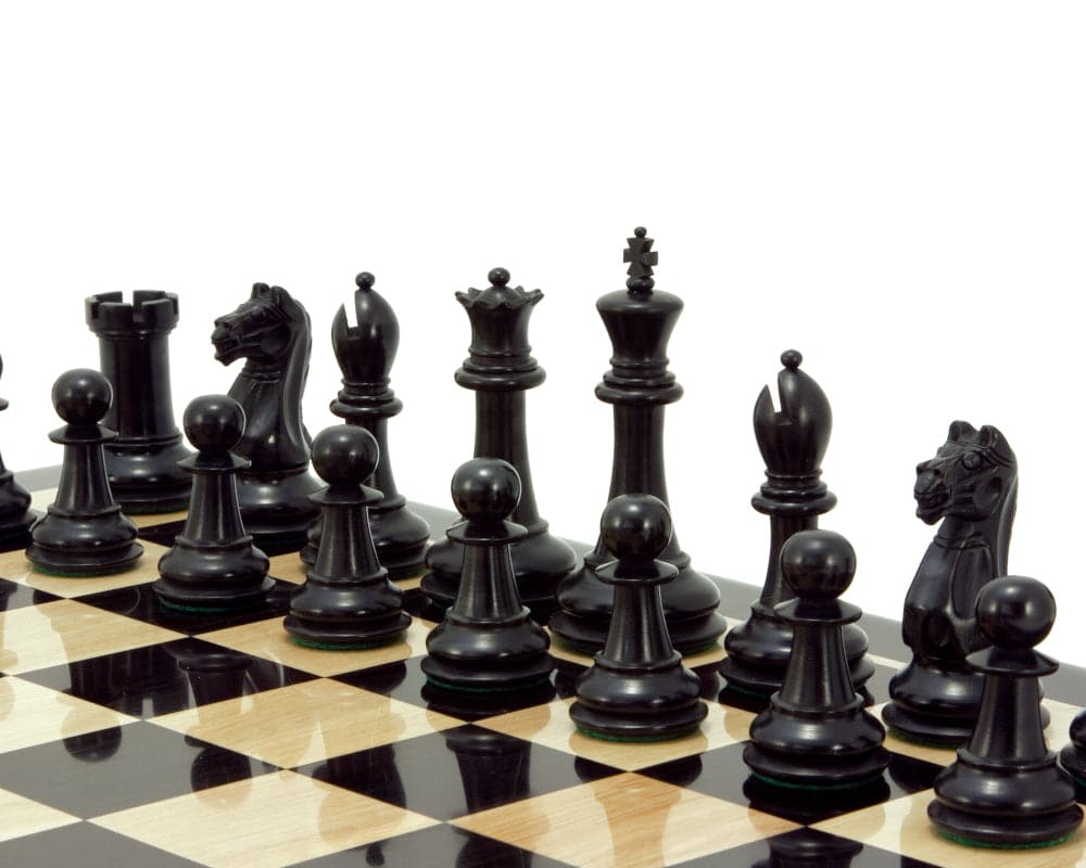 Intricately designed ebonised boxwood chess pieces on a chessboard, including a 3.75 inch king, hand crafted and finished.