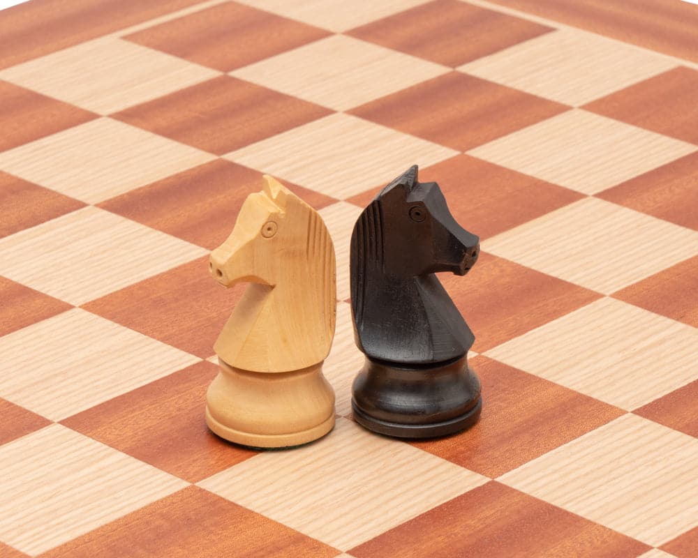 Black and white knight pieces on a mahogany and birch chessboard from the Down Head Knight Tournament Edition Chess Set.